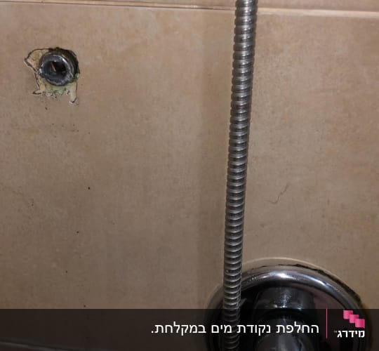 ברז מתכת עם צינור גמיש על קיר קרמיקה